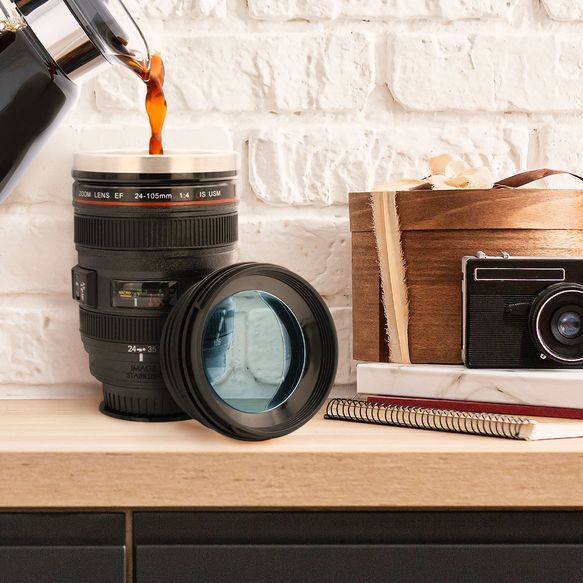 Jemand schüttet Kaffee in ein Kameraobjektiv, das sich als Thermobecher entpuppt.