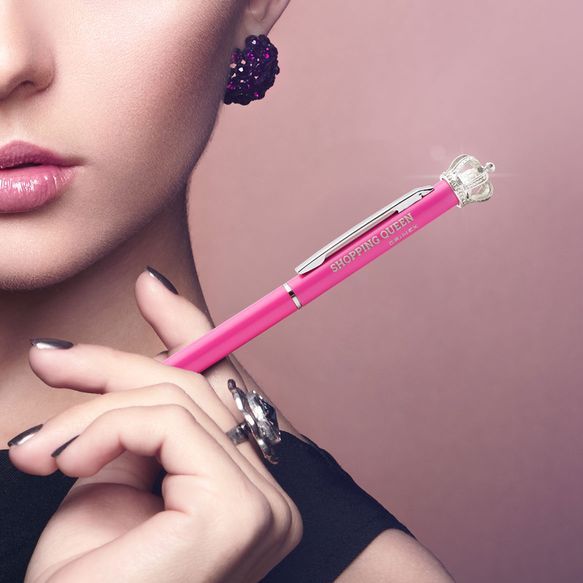 Eine junge Frau hält einen Kugelschreiber elegant zwischen ihren Fingern.